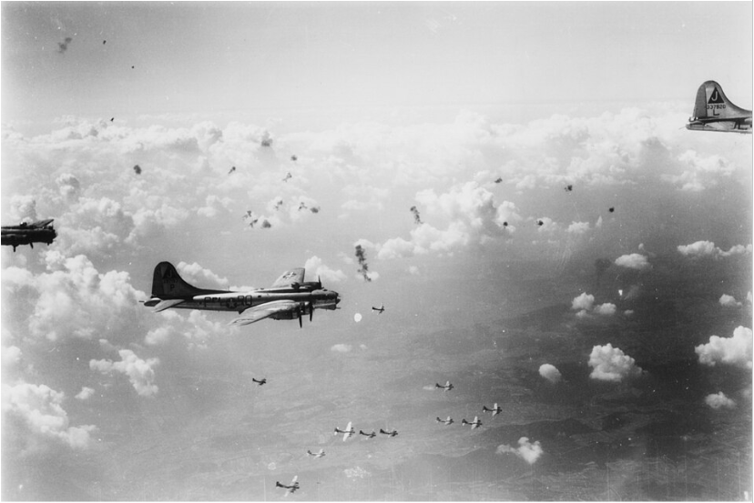 351st Bomb Group B-17 Flying Fortresses thundering through bursts of anti-aircraft fire over enemy territory. They would likely be met by interceptor aircraft once the flak subsided (Photo By: USAAF Photographer).

